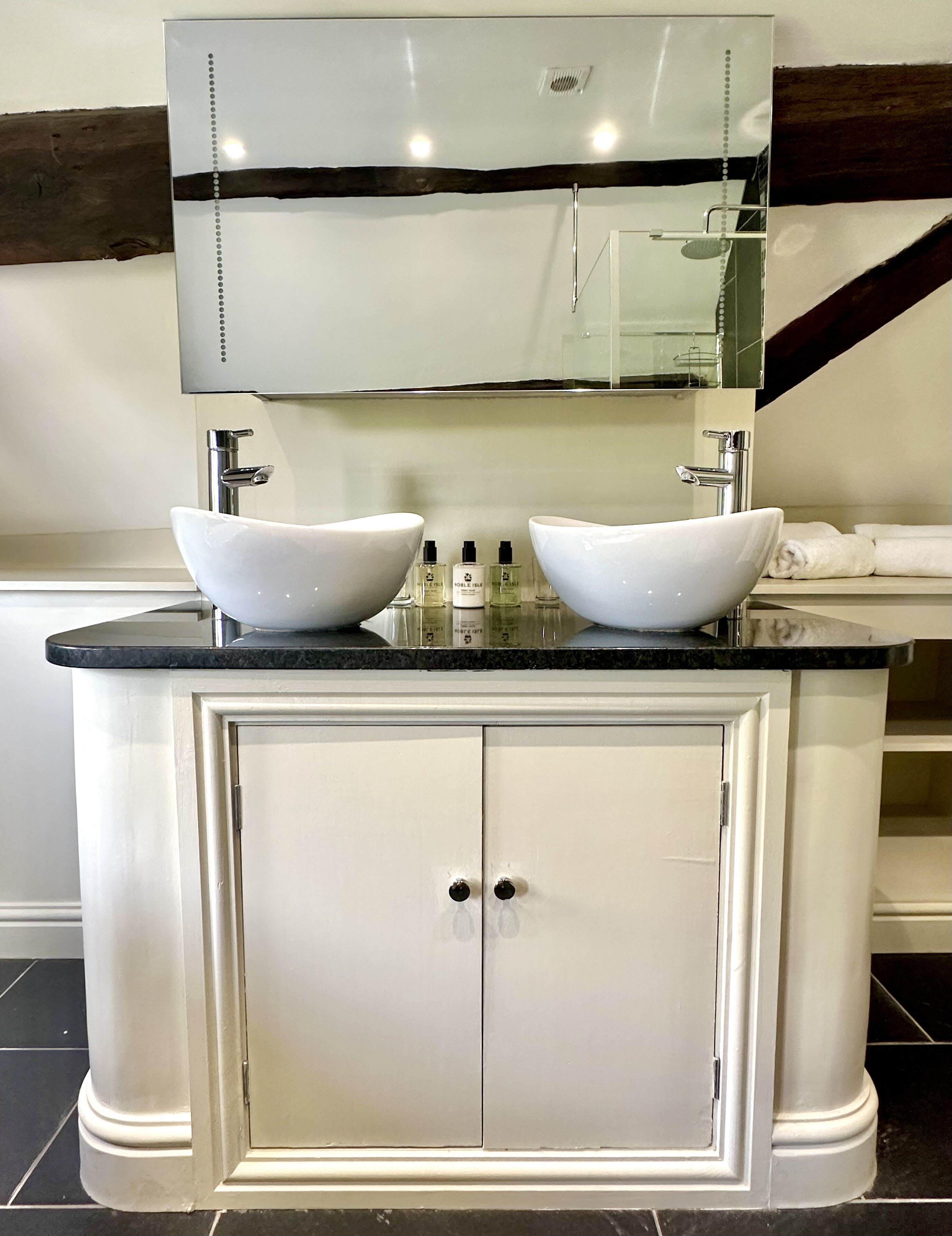 Une salle de bain avec un meuble-lavabo à deux vasques, un miroir au-dessus du lavabo et un meuble de rangement en dessous.