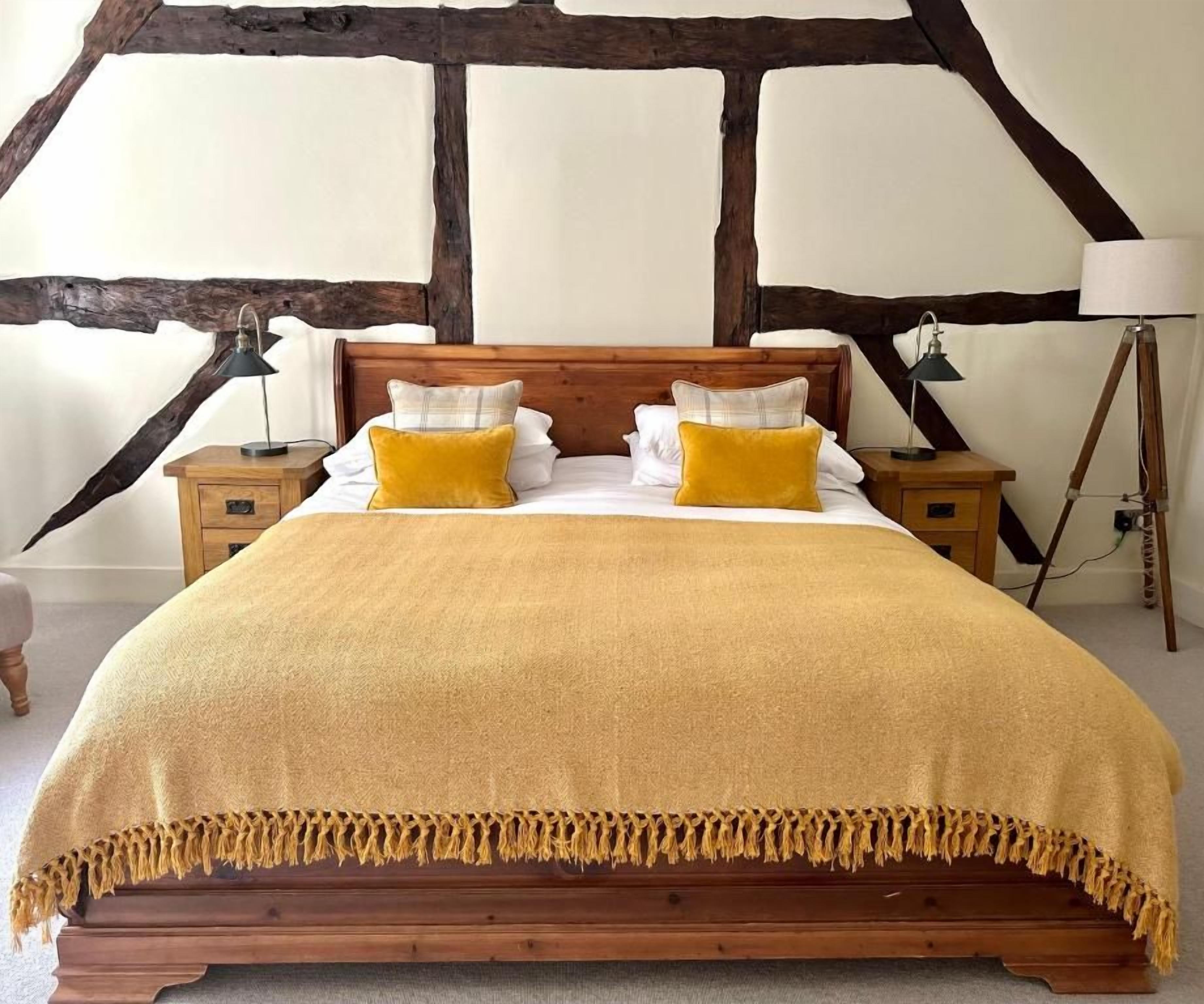 Una cama con cabecera de madera, dos mesitas de noche y una lámpara.