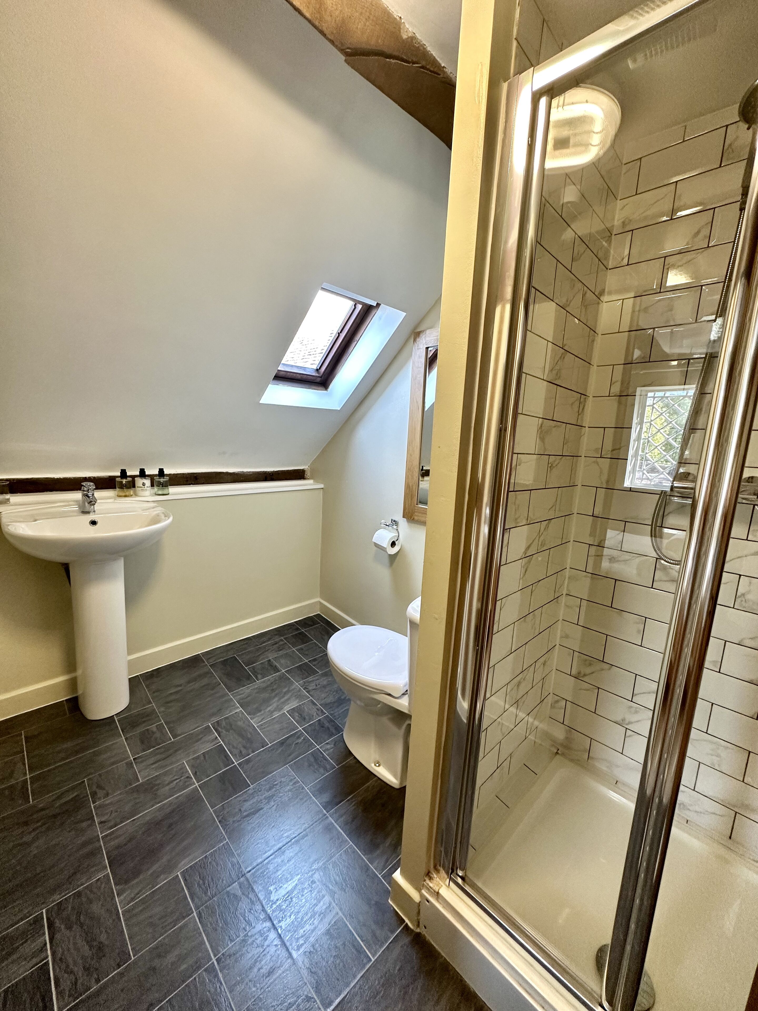 Un bagno con lavabo a piedistallo, wc e box doccia in vetro.