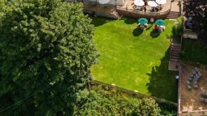 An aerial view of a traditional English village with a prominent pub featuring outdoor seating and a well-maintained lawn.