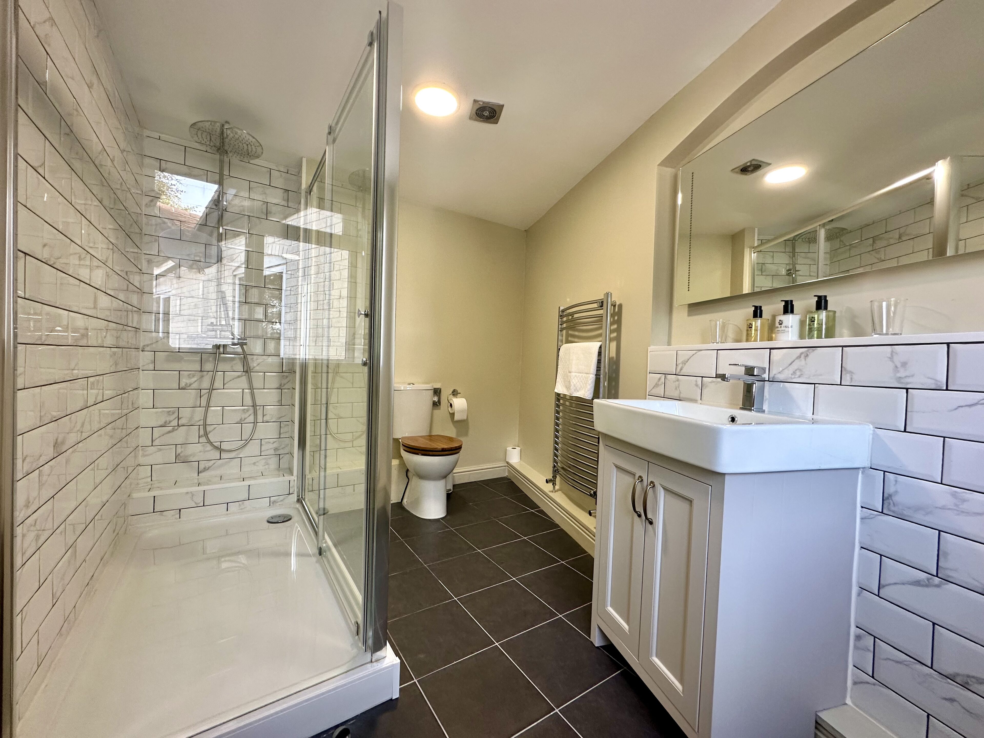 Une salle de bain moderne avec une douche à parois de verre, des toilettes et un meuble-lavabo avec un miroir.