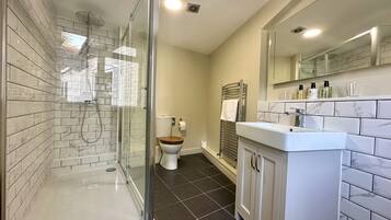Une salle de bain moderne avec une douche à parois de verre, des toilettes et un meuble-lavabo avec un miroir.