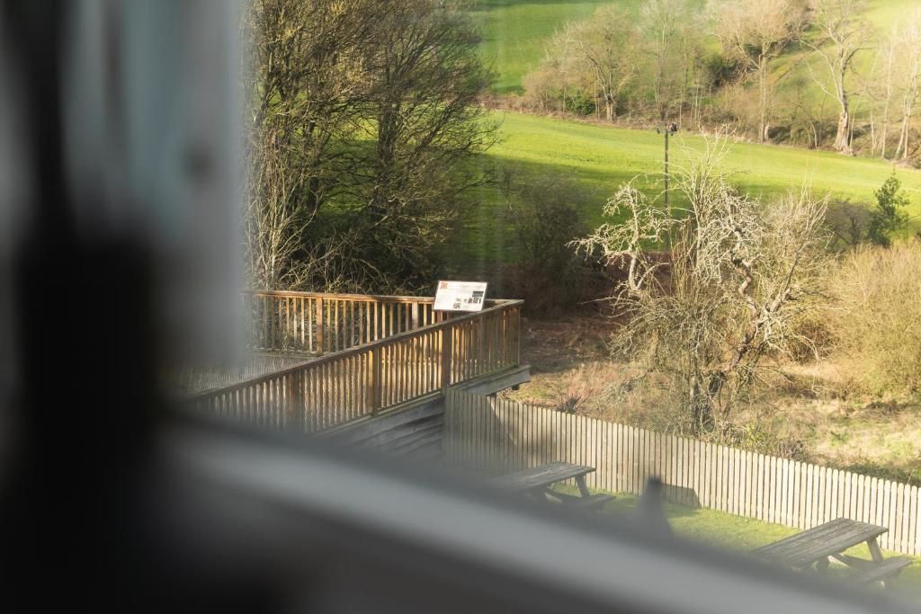A wooden deck with a bench, overlooking a grassy area with trees.