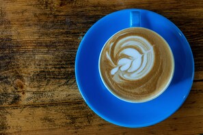 A blue cup of coffee with latte art on a wooden table. - The Manor at Abberley (Worcester)