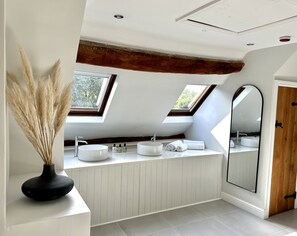A modern bathroom with skylights, a large mirror, and a white vanity with two sinks. - The Manor at Abberley (Worcester)