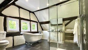 A modern bathroom with a glass-enclosed shower, a freestanding bathtub, and a toilet. - The Manor at Abberley (Worcester)