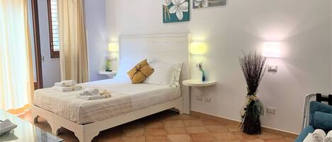 A neatly arranged bedroom with a bed, bedside tables, and a nightstand.