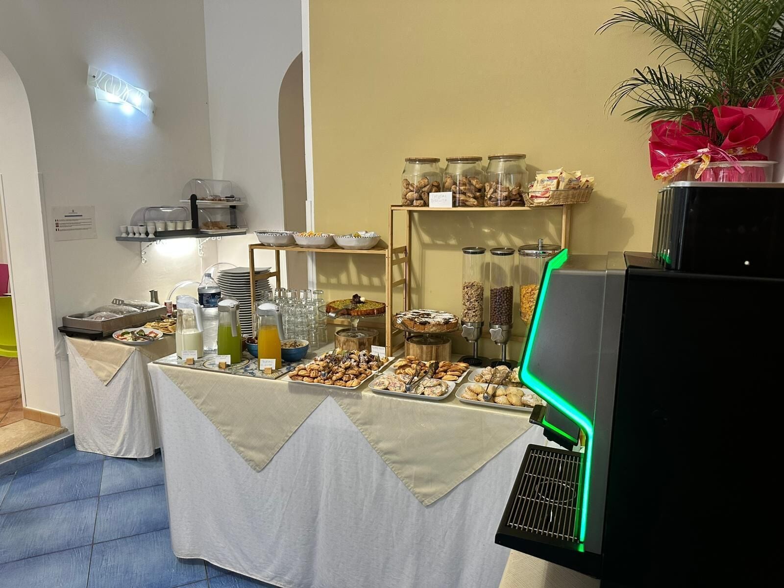 Montaje de bufé con diversas opciones de comida, una estación de café y una planta decorativa.