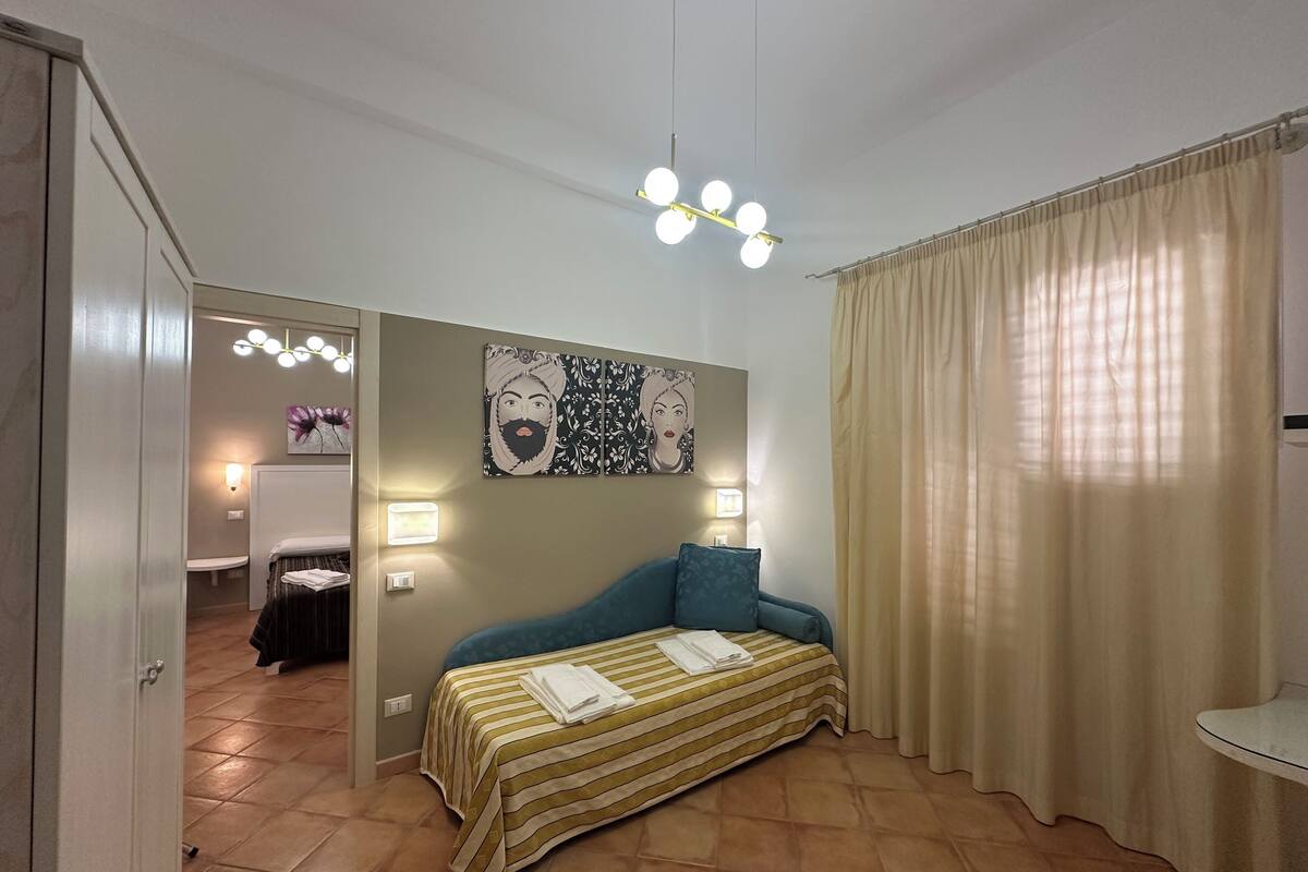 Une chambre à coucher comprenant un lit, une table de chevet, un miroir et un luminaire fixé au mur.