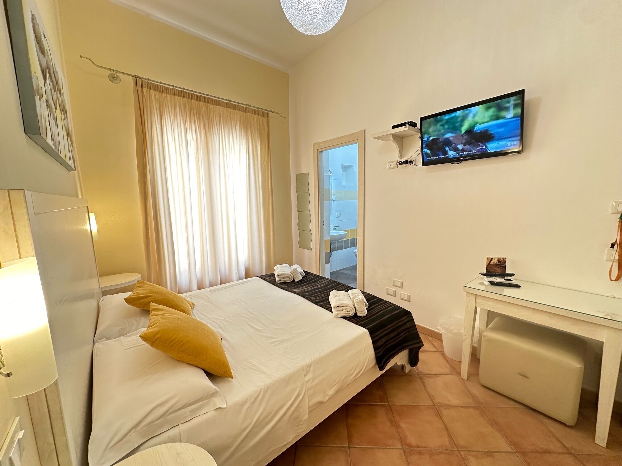 Ein Hotelzimmer mit Bett, Schreibtisch, Fernseher und einem durch die Tür sichtbaren Badezimmer.