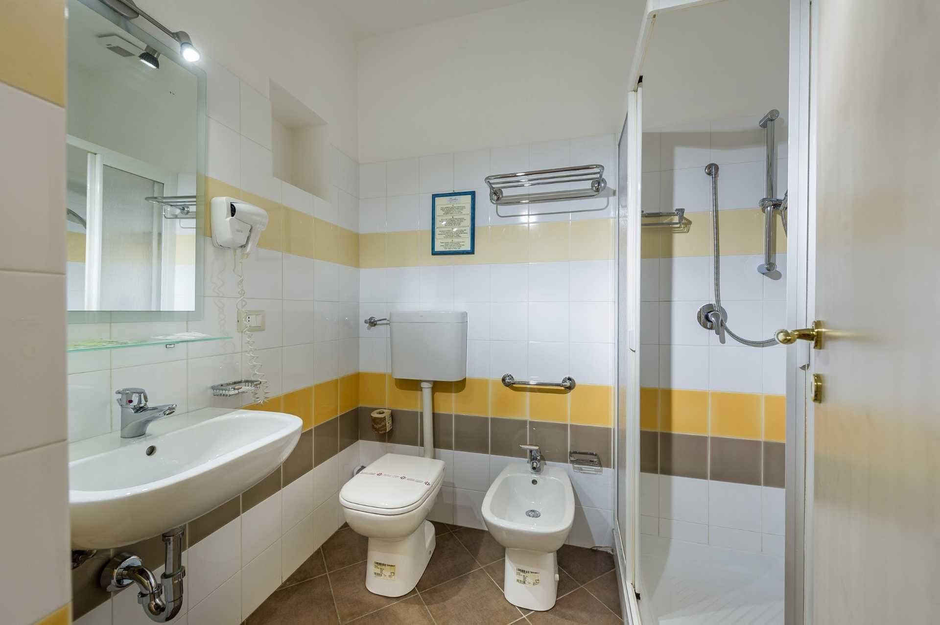A bathroom with a sink, toilet, bidet, and shower.