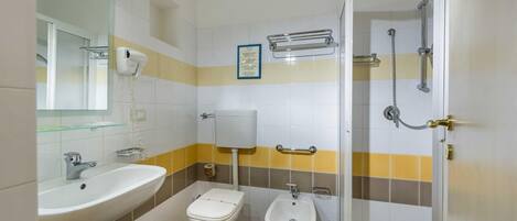A bathroom with a sink, toilet, bidet, and shower.