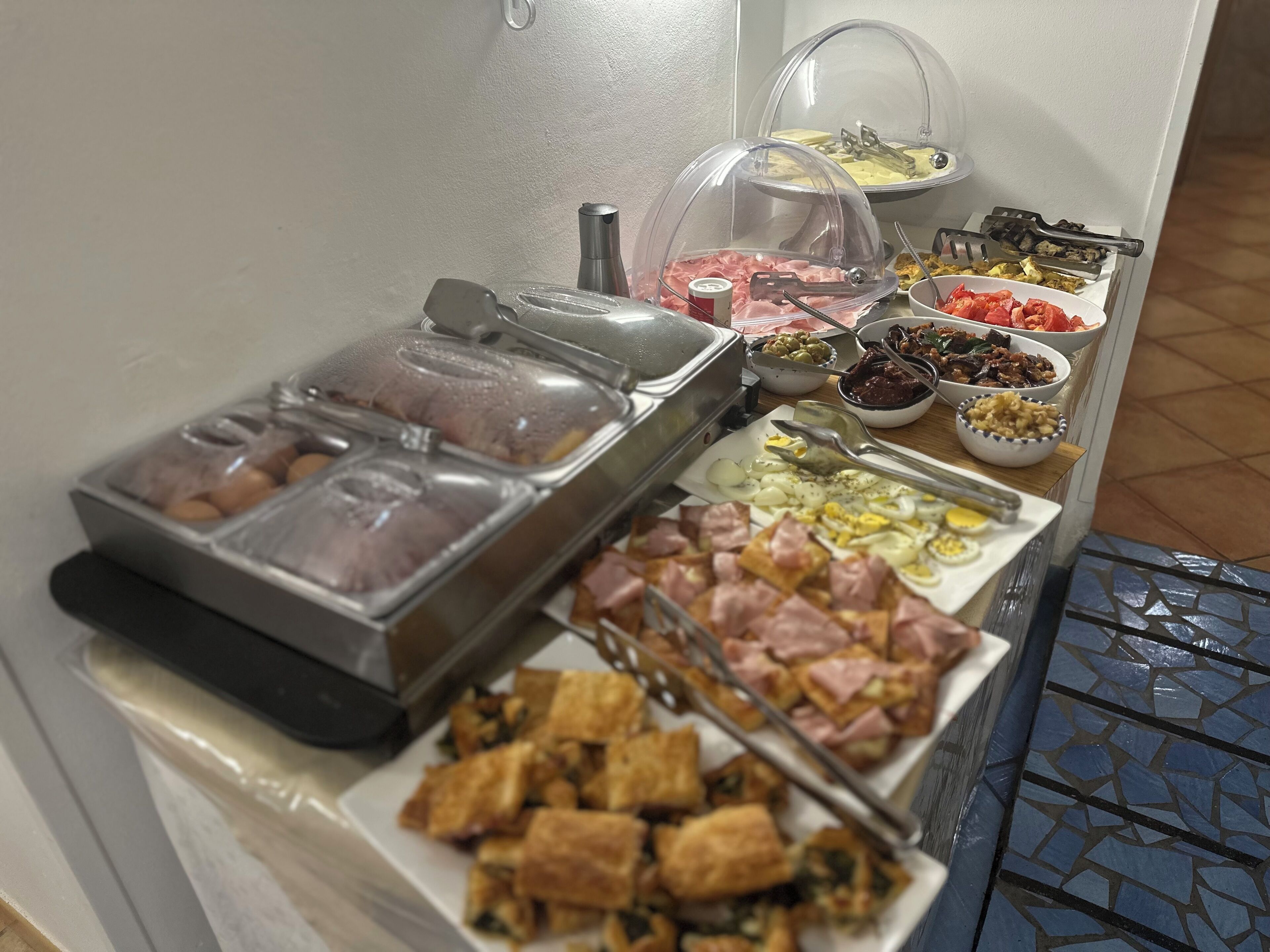 Un bufé con una variedad de alimentos, incluyendo carnes, huevos y ensaladas.
