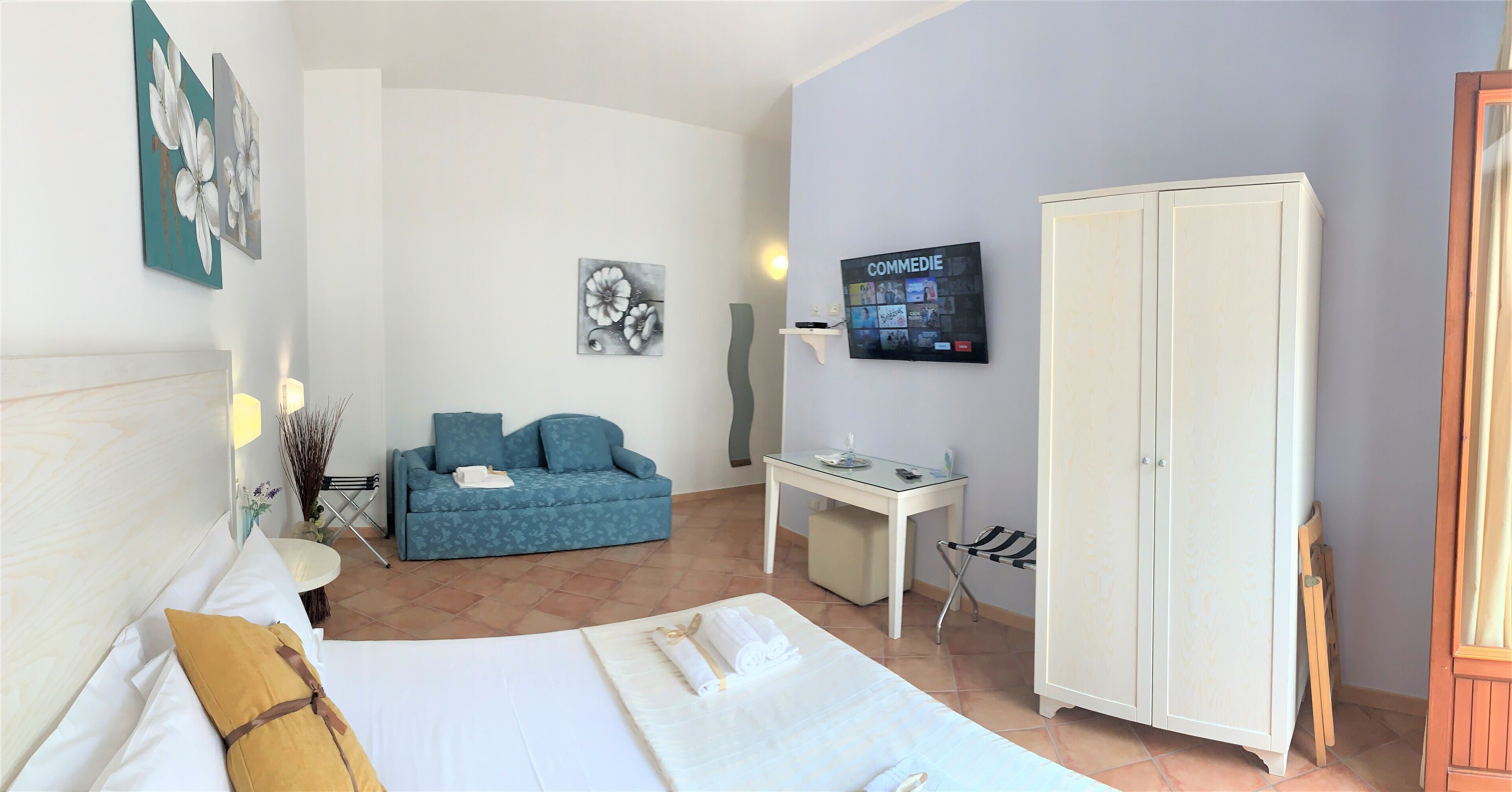 A hotel room with a bed, a sofa, a desk, and a wardrobe.