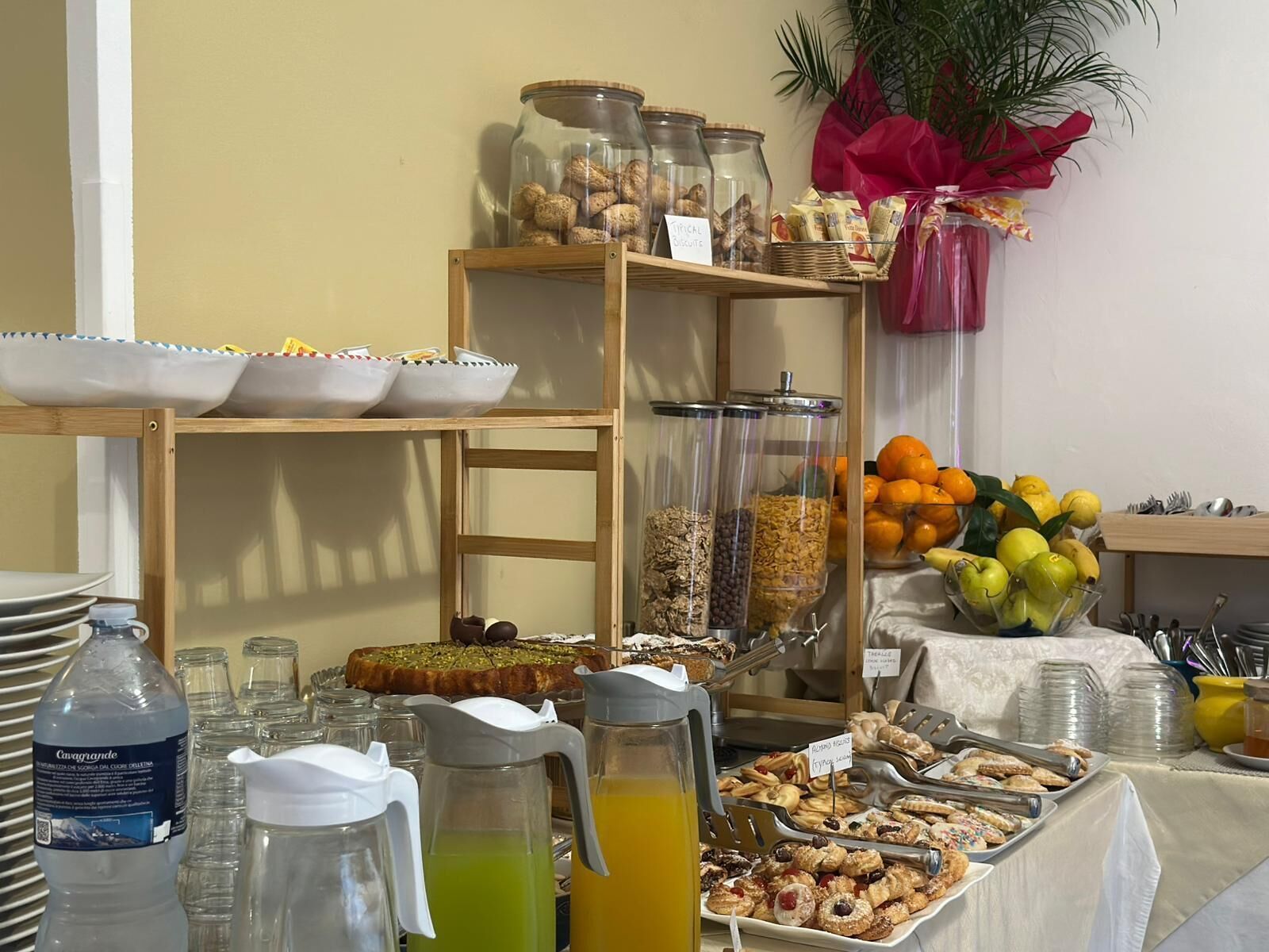 Een buffetopstelling met diverse soorten eten, waaronder fruit, ontbijtgranen en gebak.
