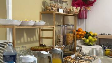 A buffet setup with various food items, including fruits, cereals, and pastries.