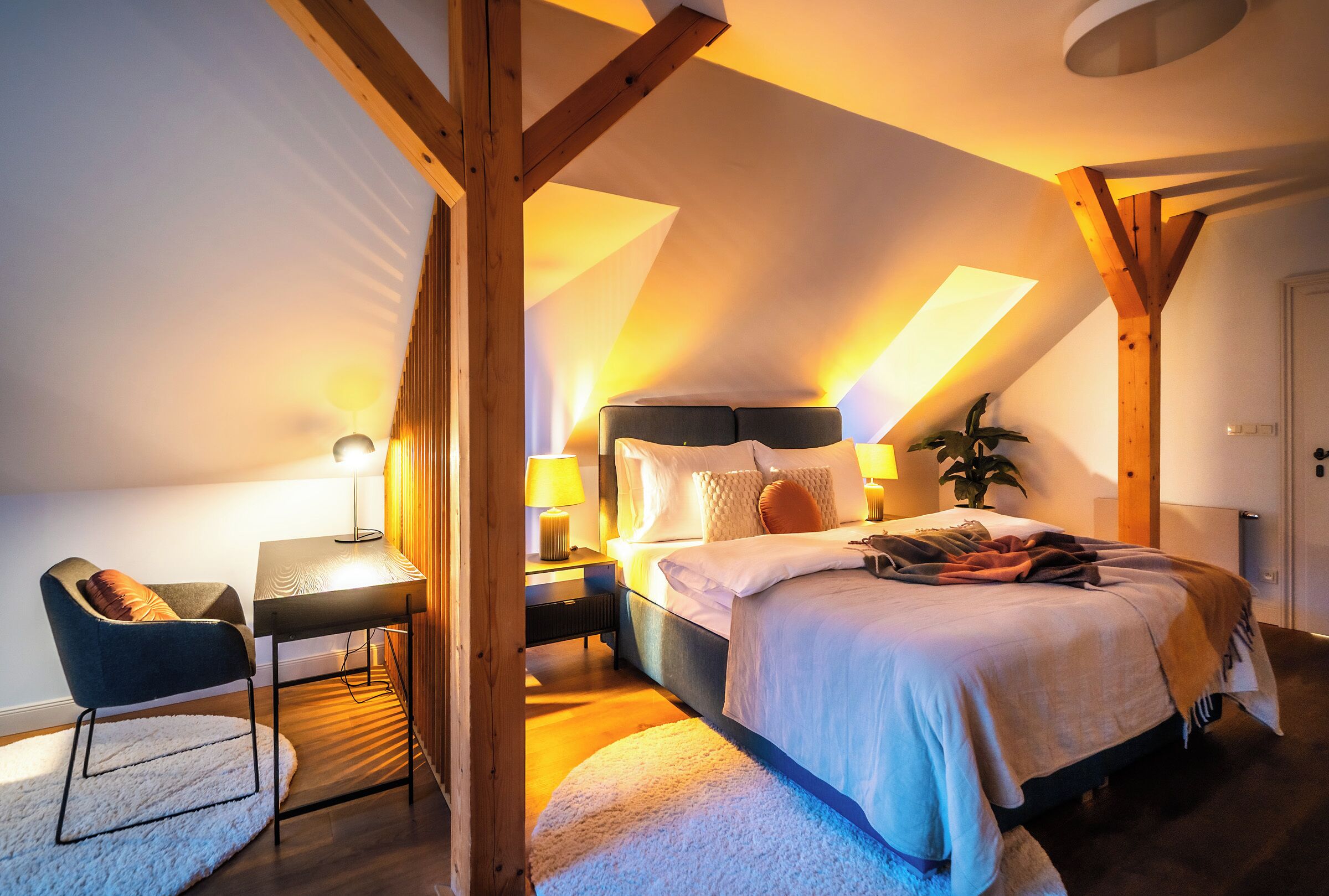 A cozy bedroom with a bed, bedside tables, a chair, and a lamp.