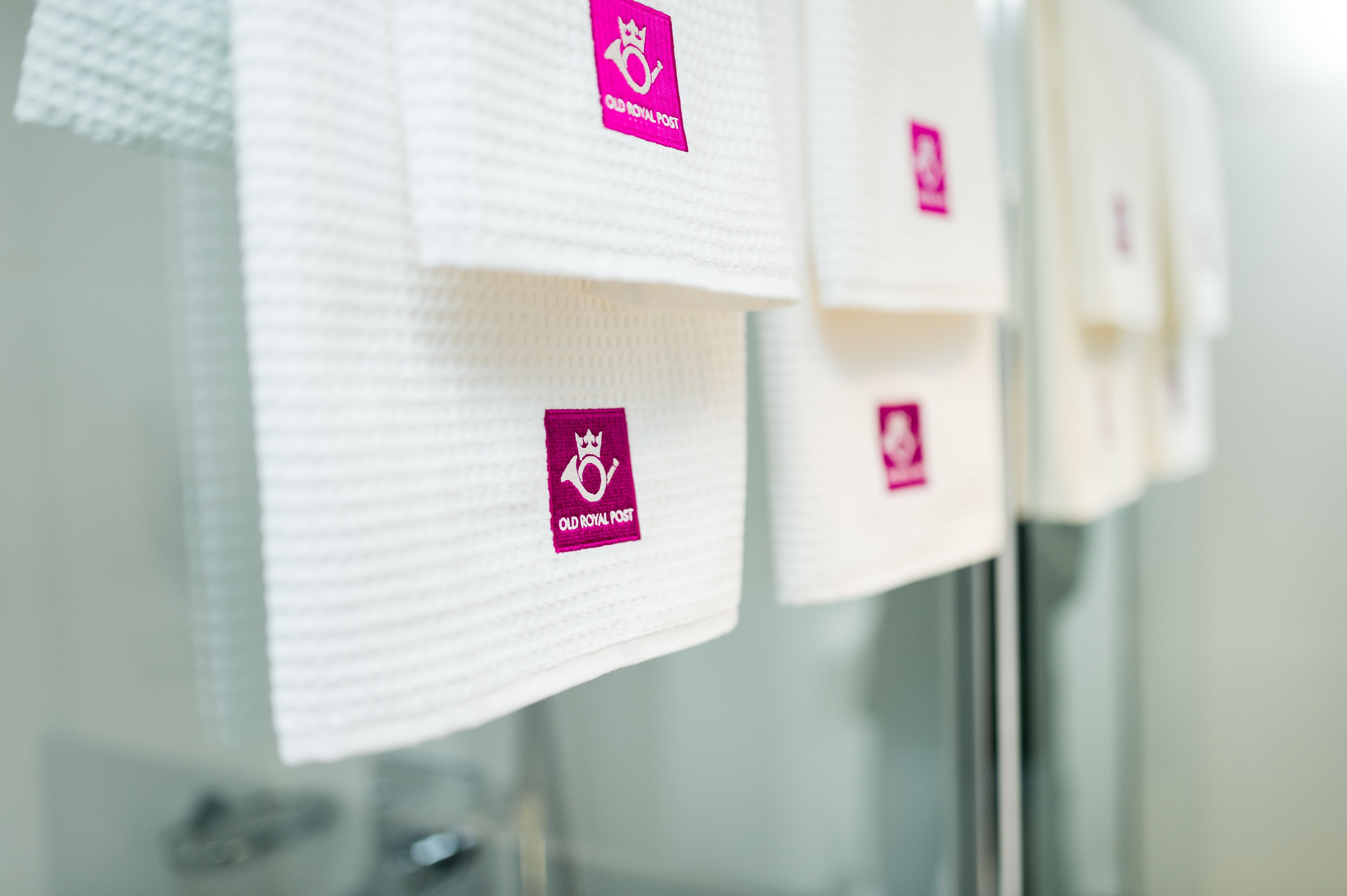 A row of white towels hanging on a rack with a logo that reads "Old Royal Post."