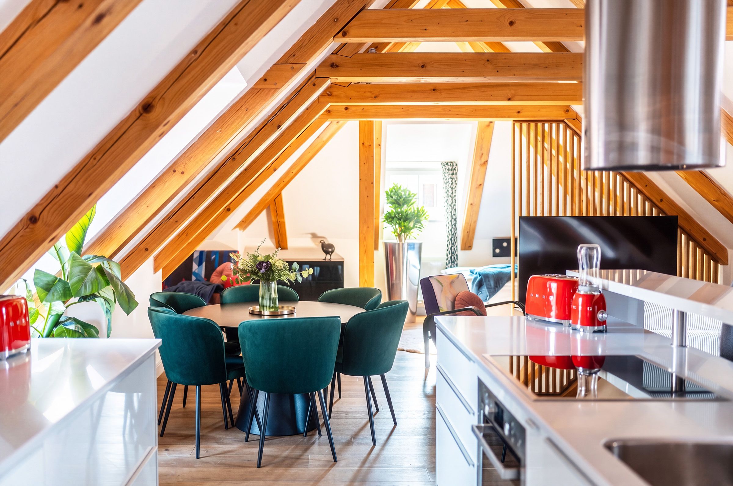 Cozinha moderna com área de refeições, vigas de madeira e vista para a sala de estar.