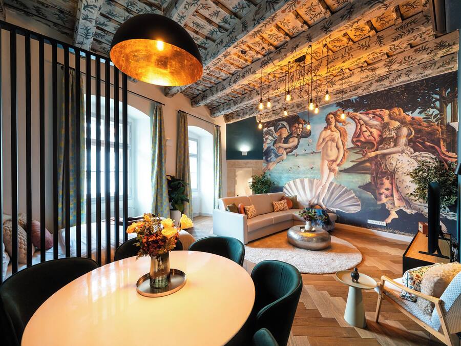 A modern living room with a large mural, a dining area with a round table, and a cozy seating arrangement.