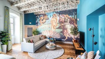 Una sala de estar con un mural grande, un sofá, una mesa de centro y un televisor.