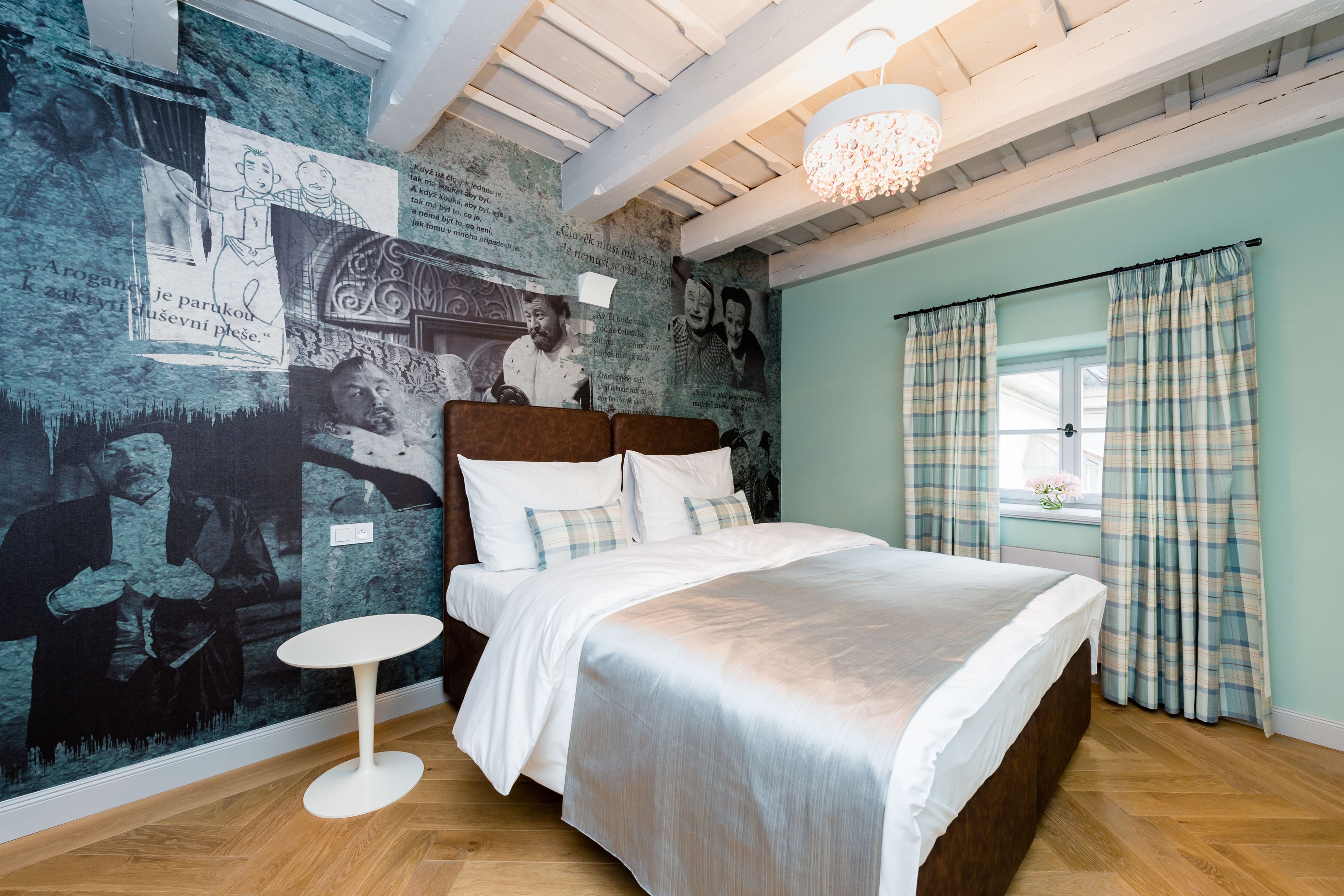 A bedroom with a bed, a round table, and a wall with artwork.