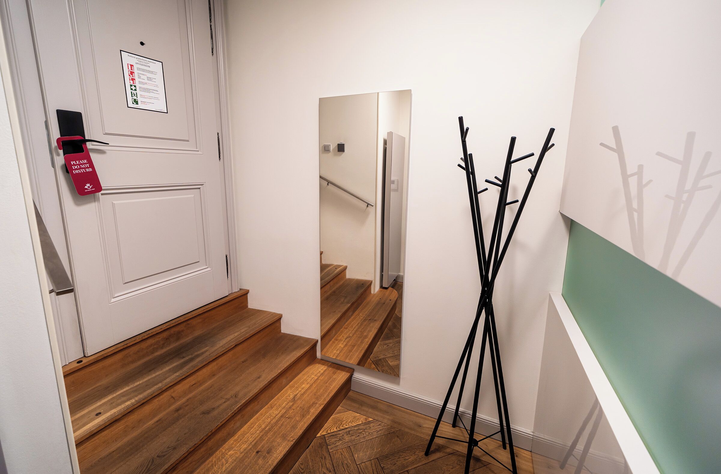 Um corredor com porta, espelho e cabideiro.
