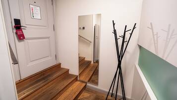 Um corredor com porta, espelho e cabideiro.