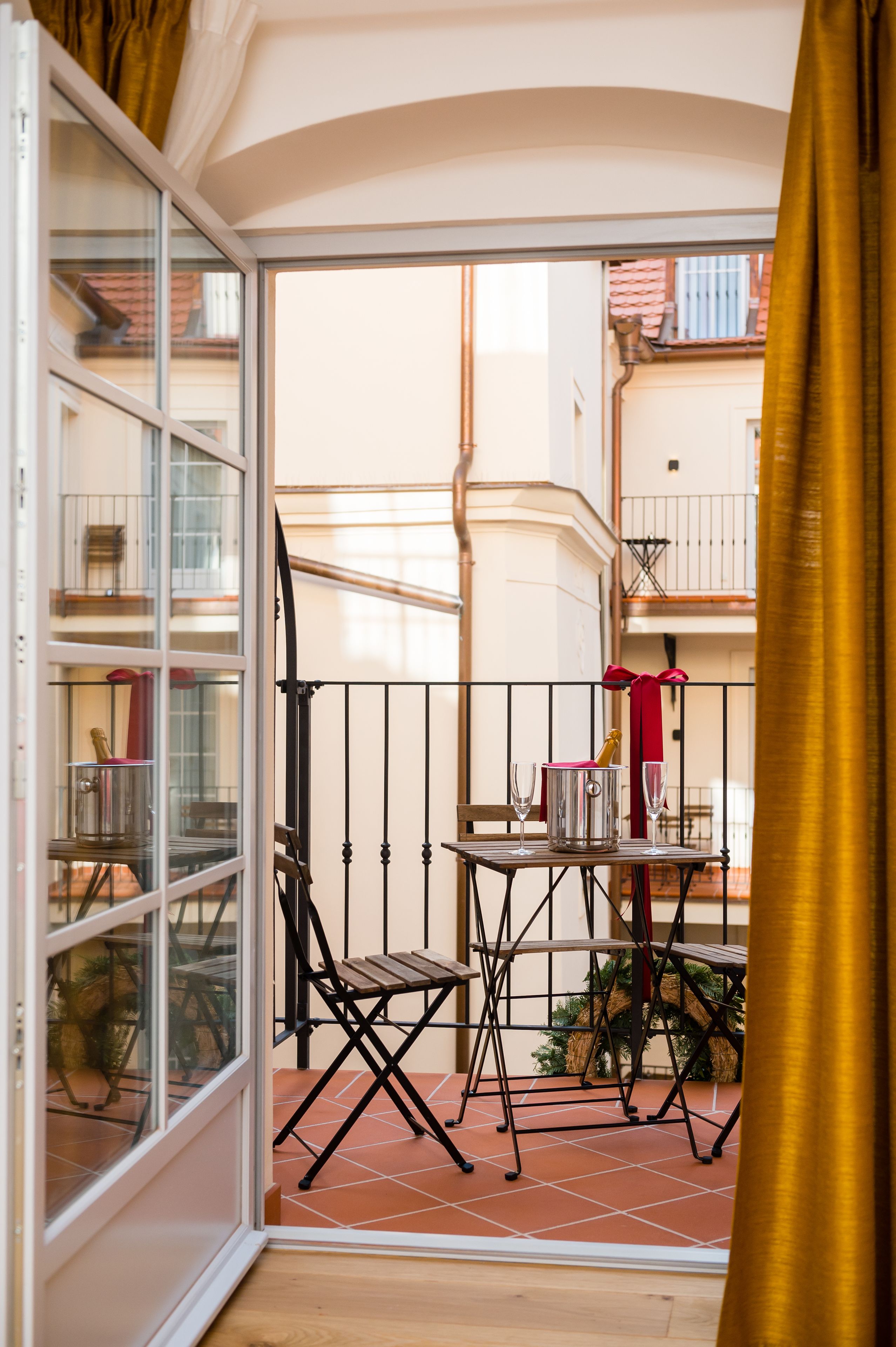 A balcony with a table set for two, a chair, and a wine glass.