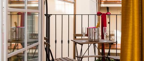 A balcony with a table set for two, a chair, and a wine glass.