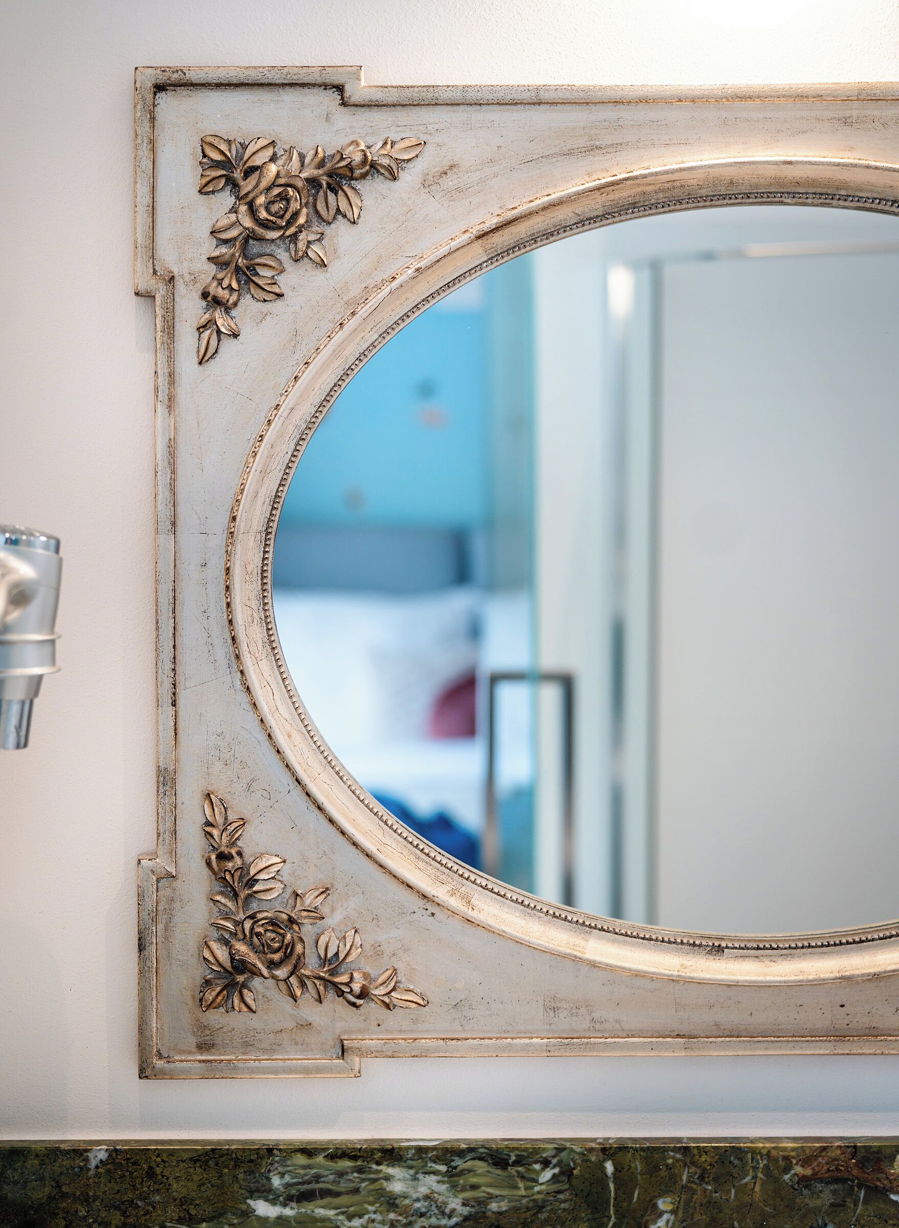Un miroir orné de motifs floraux sculptés, accroché à un mur blanc.