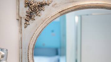 Un miroir orné de motifs floraux sculptés, accroché à un mur blanc.