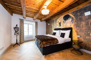 Quarto com teto de madeira, uma cama grande, um mural na parede e um abajur.