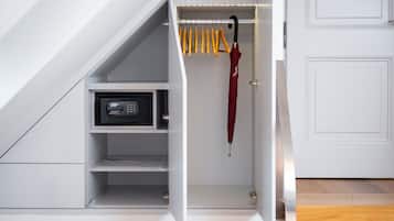 A modern closet with a built-in safe, a hanging rack with yellow handles, and a red umbrella.