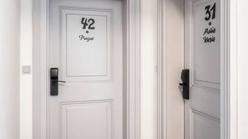 Un couloir avec deux portes, l’une portant l’inscription « 42 Prague » et l’autre « 31 Mario Terezio ». Les deux portes ont des poignées noires et sont peintes en blanc, avec un design simple.