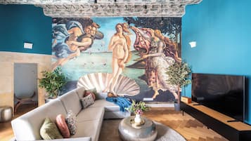 Een woonkamer met een groot muurschildering, een bank, een salontafel en een televisie.
