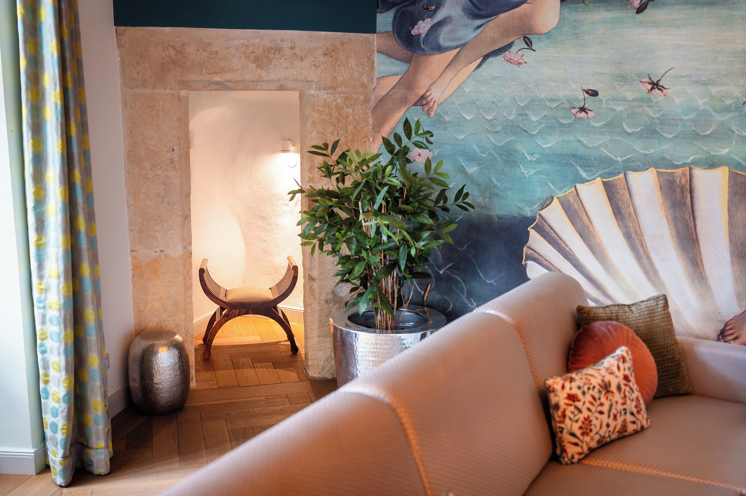 Una sala de estar acogedora con chimenea, una planta en maceta y un abanico decorativo.