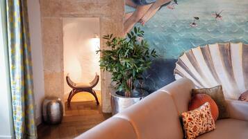 Una sala de estar acogedora con chimenea, una planta en maceta y un abanico decorativo.