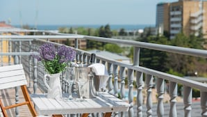 A balcony with a white table set with a pitcher, glasses, and a vase of flowers. - TM Deluxe Hotel (Sunny Beach)