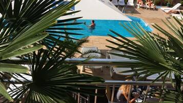 A pool area with lounge chairs and a person swimming.