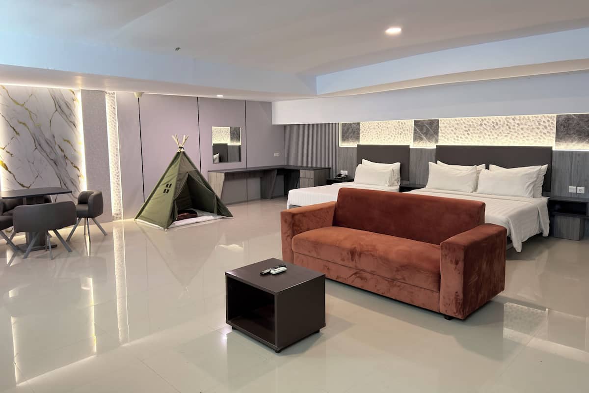 Una habitación de hotel moderna con una cama grande, un sofá marrón, una mesita, una tienda de campaña y un comedor con sillas.