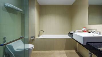 A modern bathroom with a glass shower enclosure, a white toilet, a freestanding bathtub, and a black countertop with a sink and mirror.
