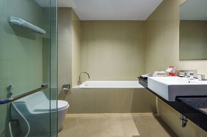 A modern bathroom with a glass shower enclosure, a white toilet, a freestanding bathtub, and a black countertop with a sink and mirror.