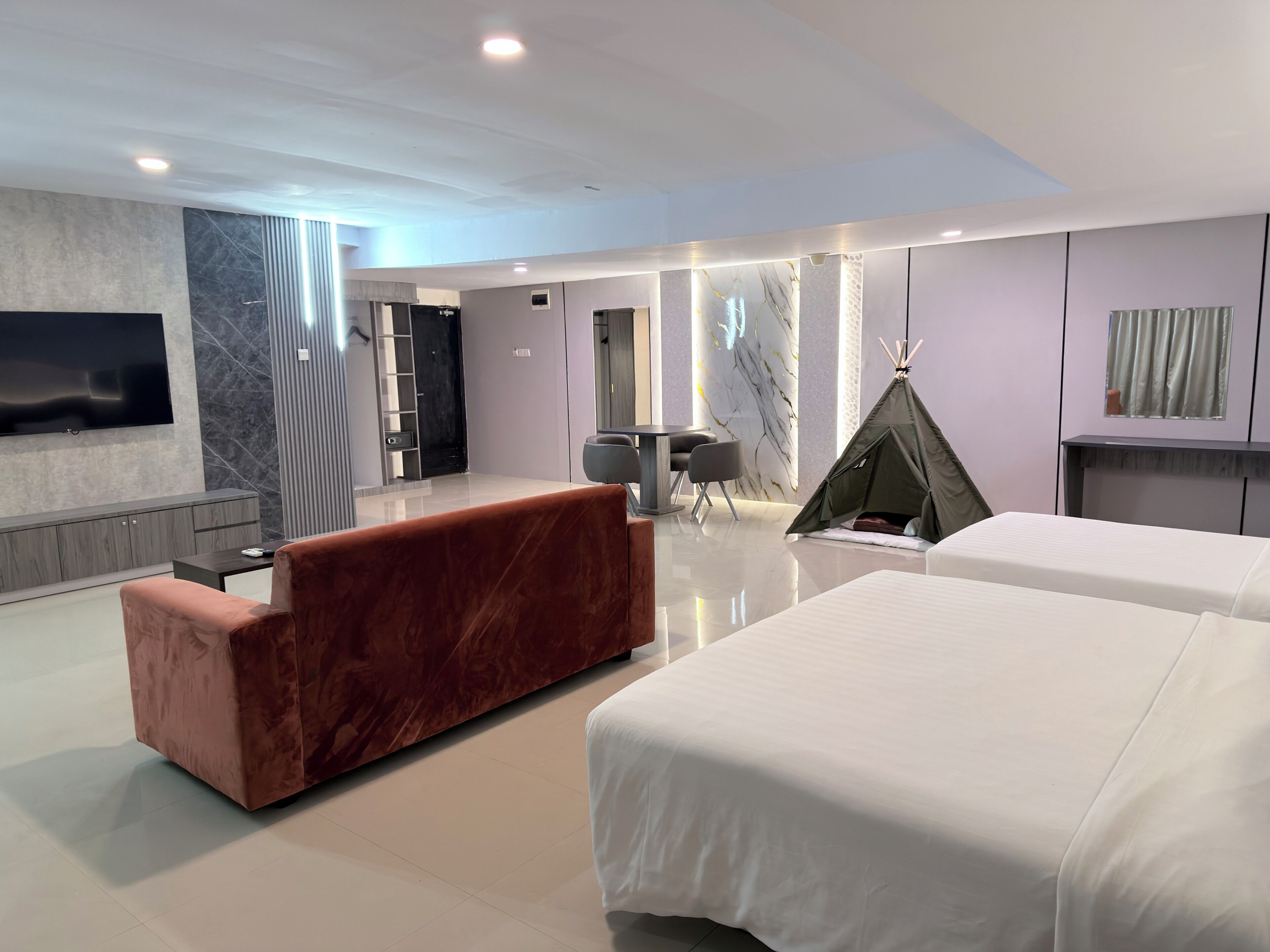 Una habitación de hotel moderna con una cama grande, un sofá, un televisor, una chimenea y una tienda de campaña.