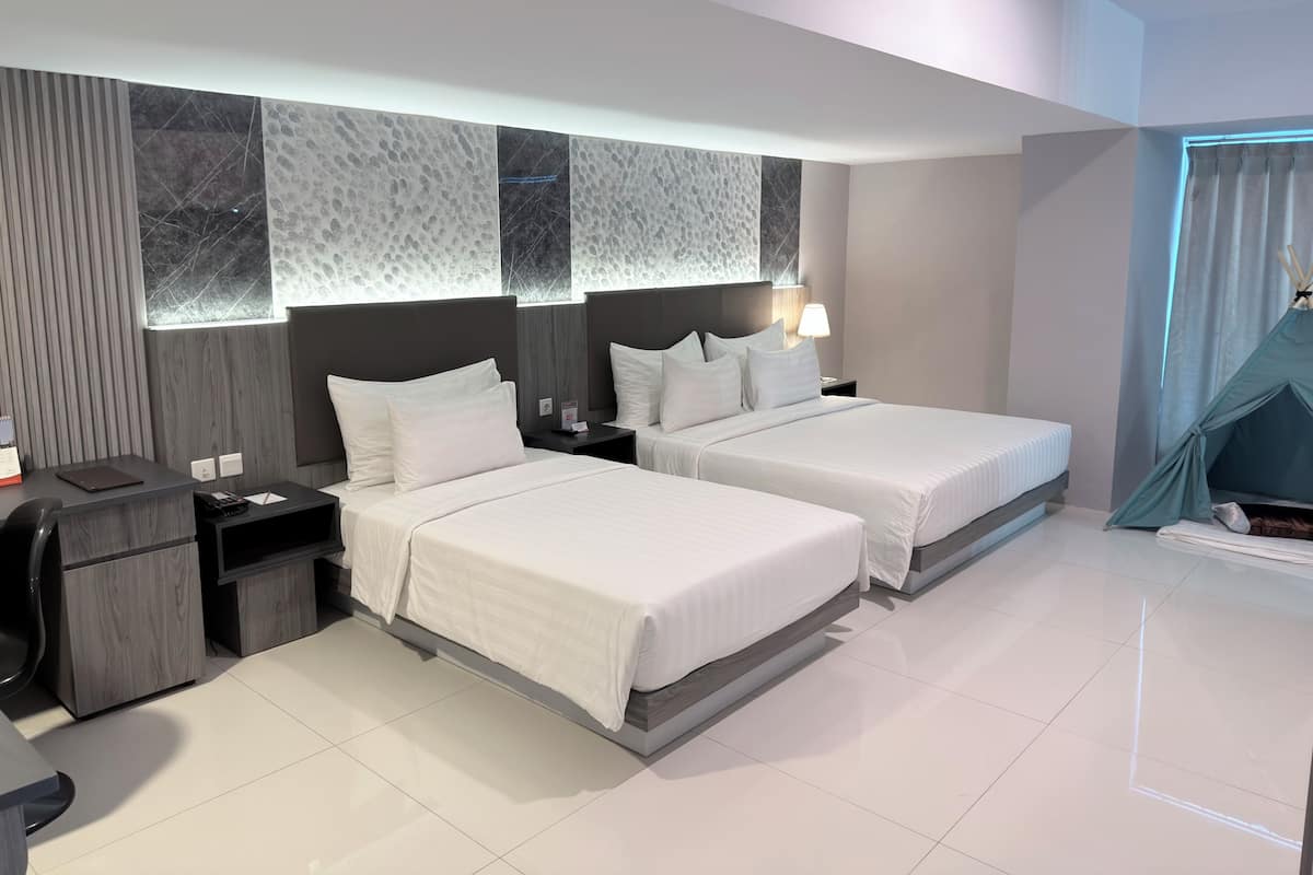 Una habitación de hotel moderna con dos camas, un escritorio, una silla y una estructura tipo tienda de campaña.