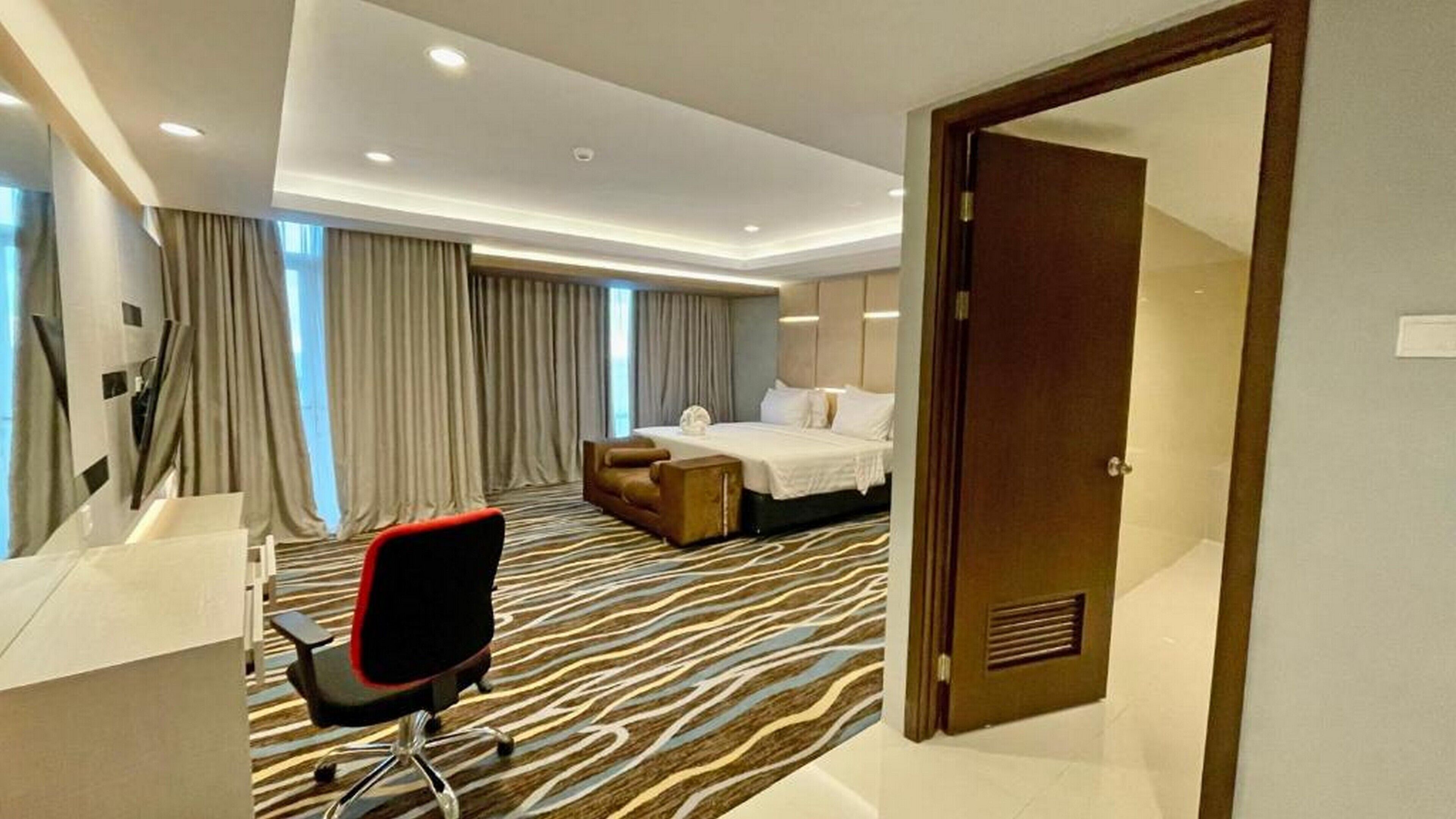 A hotel room with a bed, a desk, a chair, and a large window with curtains.