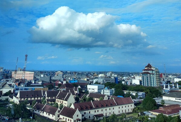 A cityscape with historical buildings, modern structures, and a large cloud in the sky.