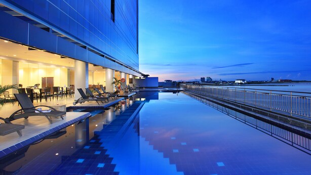 Un hôtel moderne doté d’une piscine à débordement sur le toit, d’un espace extérieur aménagé et offrant une vue sur le panorama urbain.