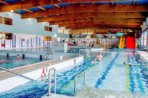 An indoor swimming pool with multiple lanes, a slide, and a dolphin mural on the wall. - Hotel Jan (Darlowo)