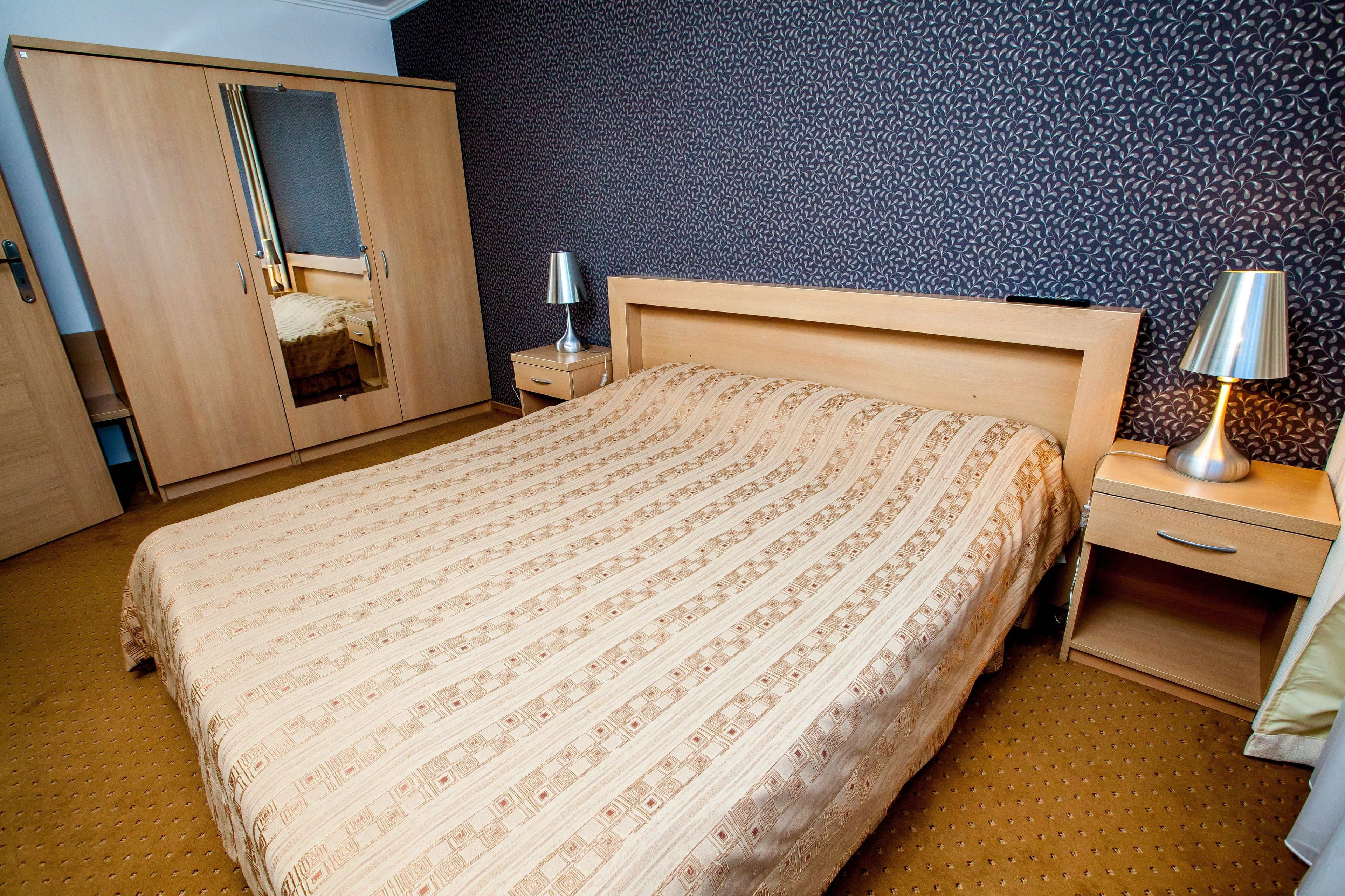 Quarto com cama, guarda-roupa, mesa de cabeceira e abajur.